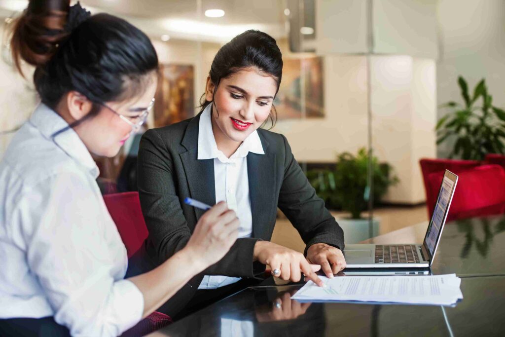 Two professionals reviewing a financial document at a laptop
