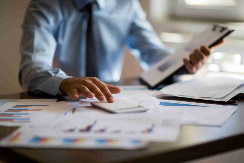 Businessman using a calculator while reviewing financial charts