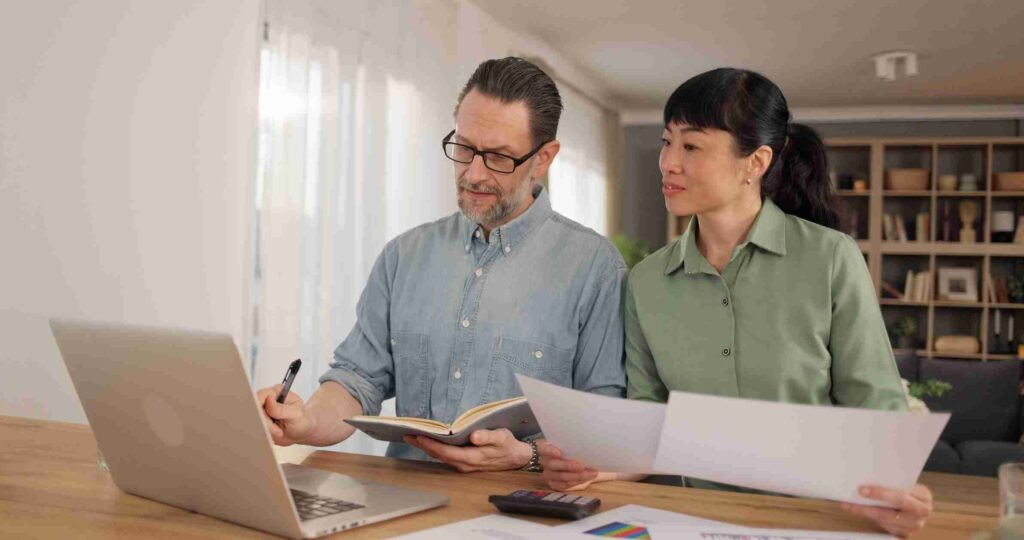 Couple reviewing financial documents together at home with a laptop
